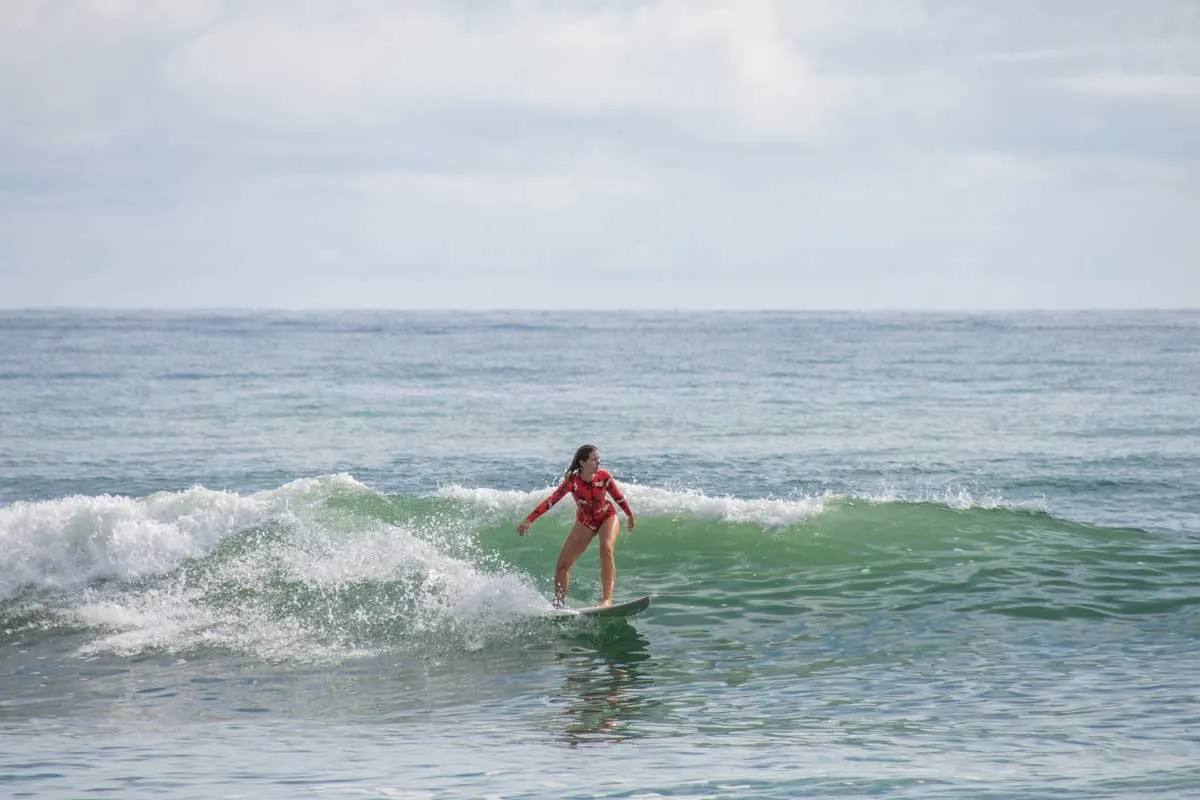 A lady surfs a wave in Dominical