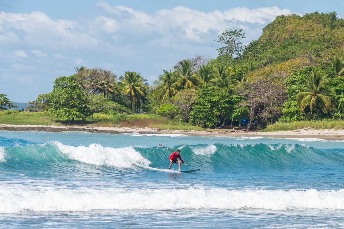 A man surfs on a beach in Santa Teresa, Costa Rica on a beautiful sunny day