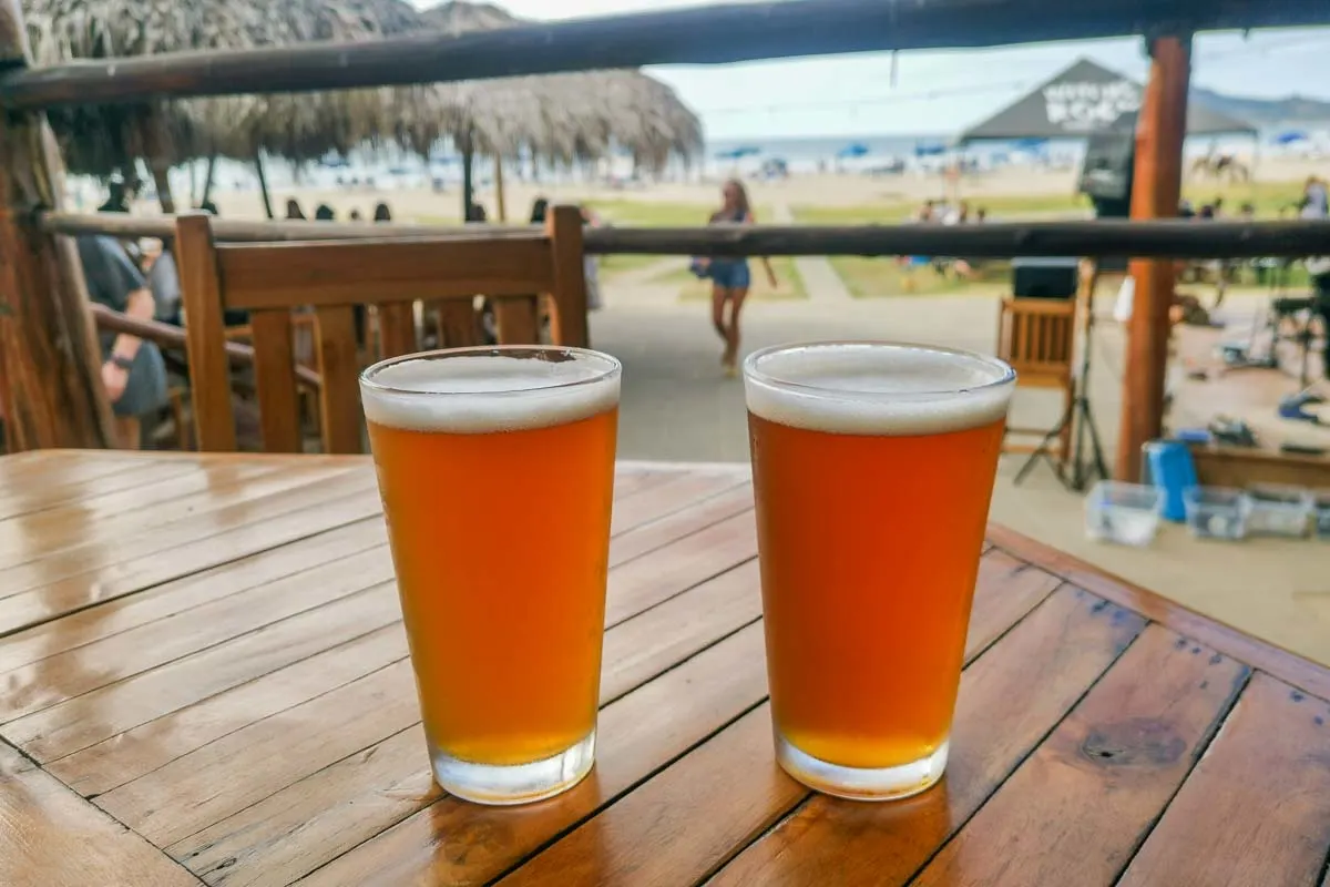 Two beers sit on a table at the beach at Volcano Brewing Co in Tamarindo