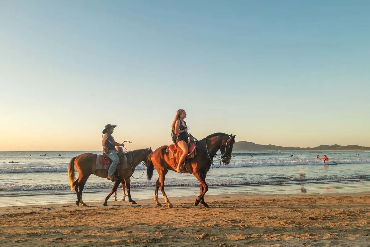 Two people ride a horse on Tamarindo Beach