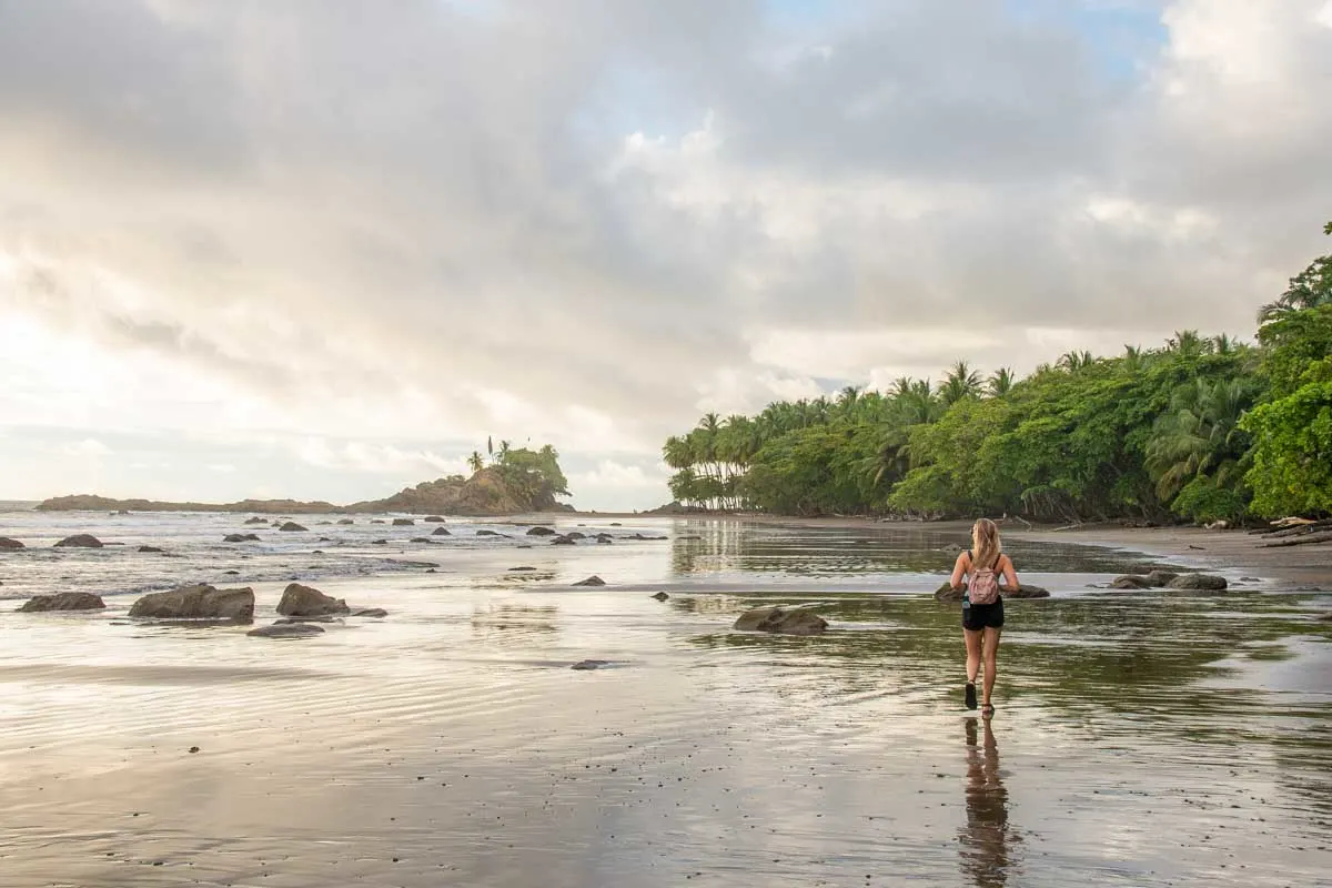 A lady walks along Dominical Beach on the south end at sunset in Costa Rica