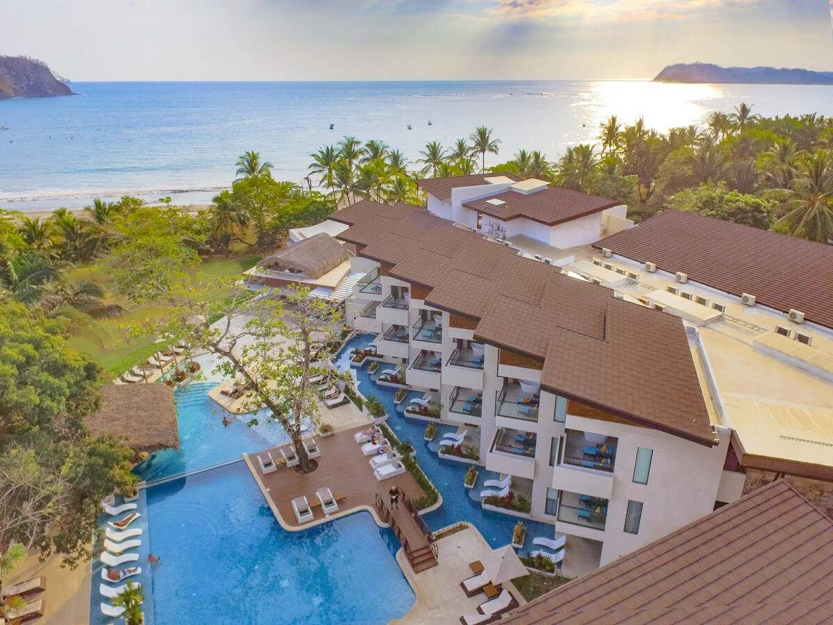 aerial view of Azura Beach Resort with the ocean and sunset in the background