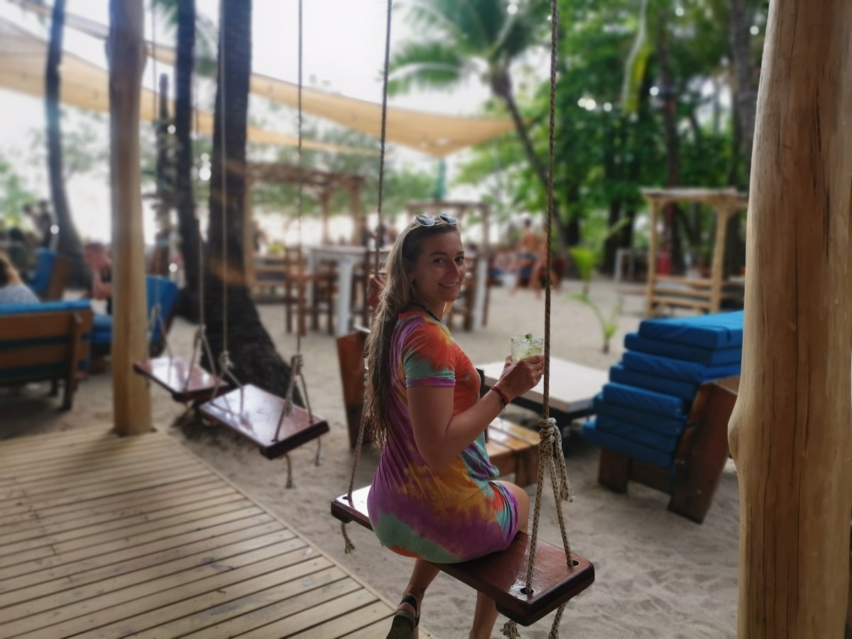 woman sits on a swing at a beach bar in Santa Teresa