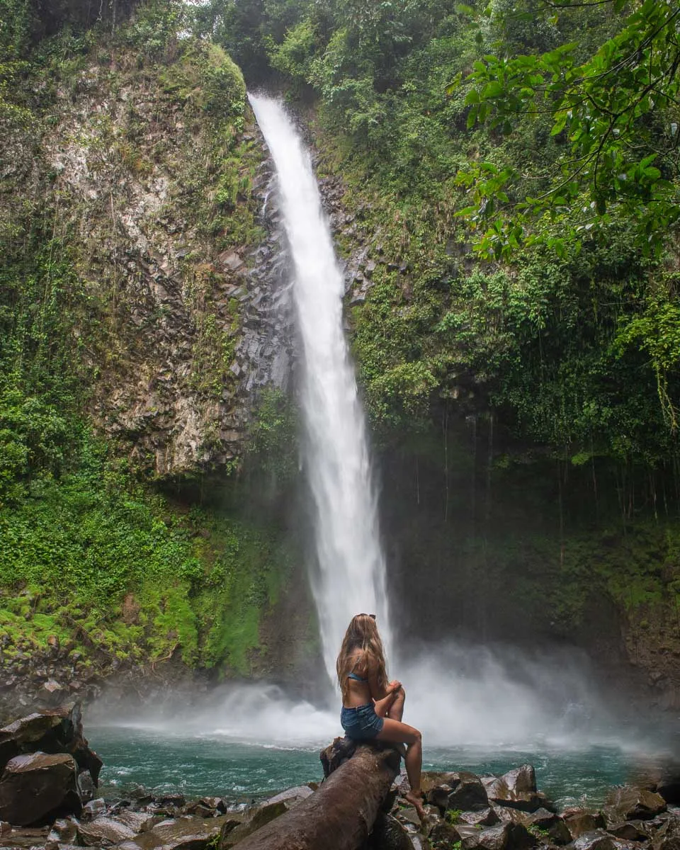 A lady sits at La Fortuna Waterfall