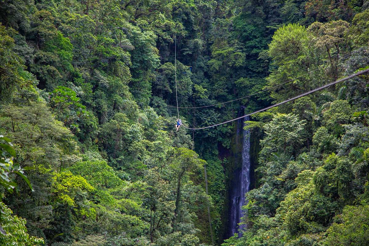 A person ziplines over La Fortuna Waterfall in La Fortuna, Costa Rica