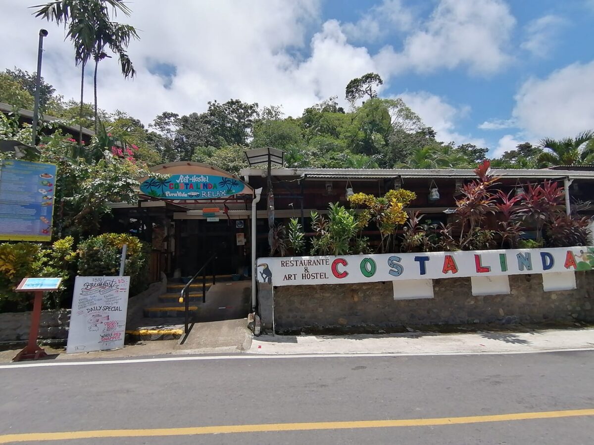 the outside and entrance to Costa Linda Art Hostel on a street in Manuel Antonio
