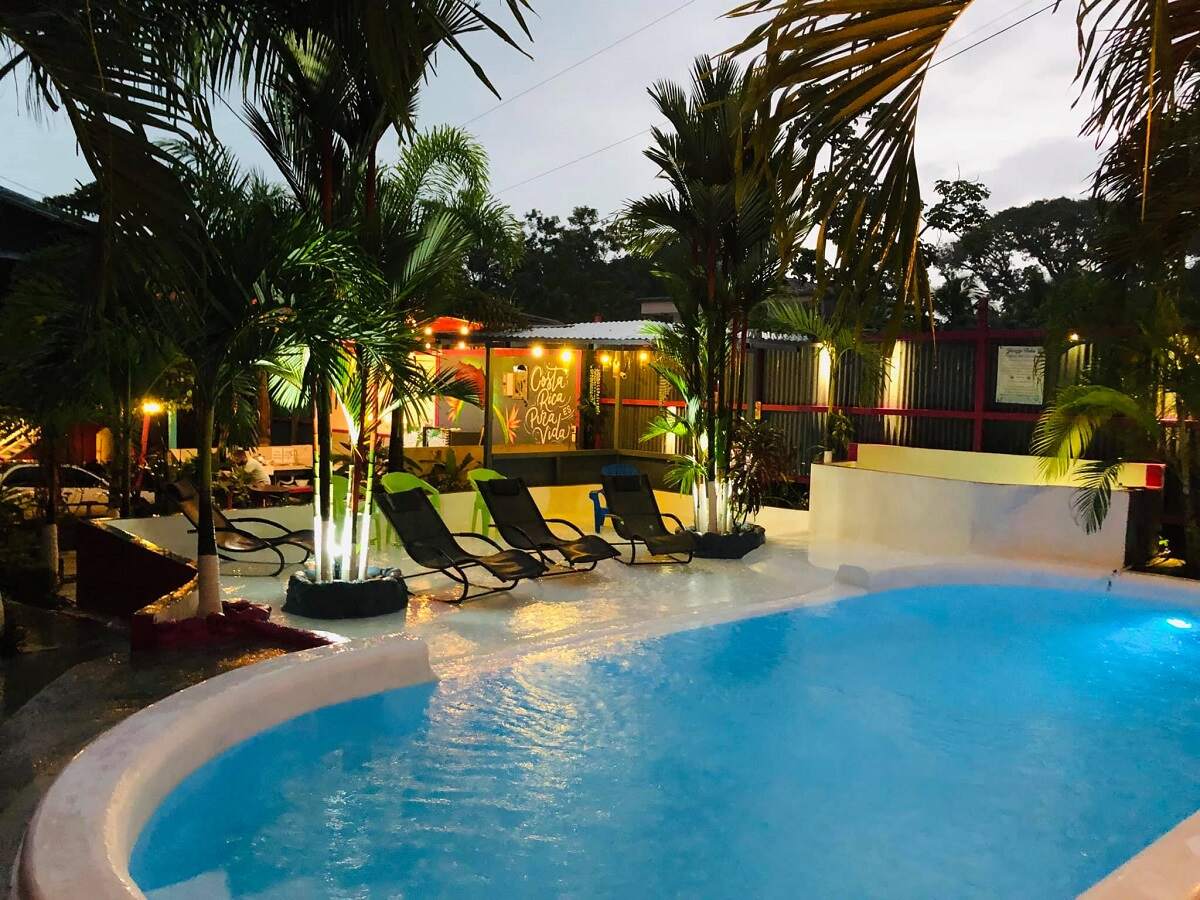 a pool in the evening surrounded by lounge chairs and fairy lights and palm trees at Millenium Manuel Antonio