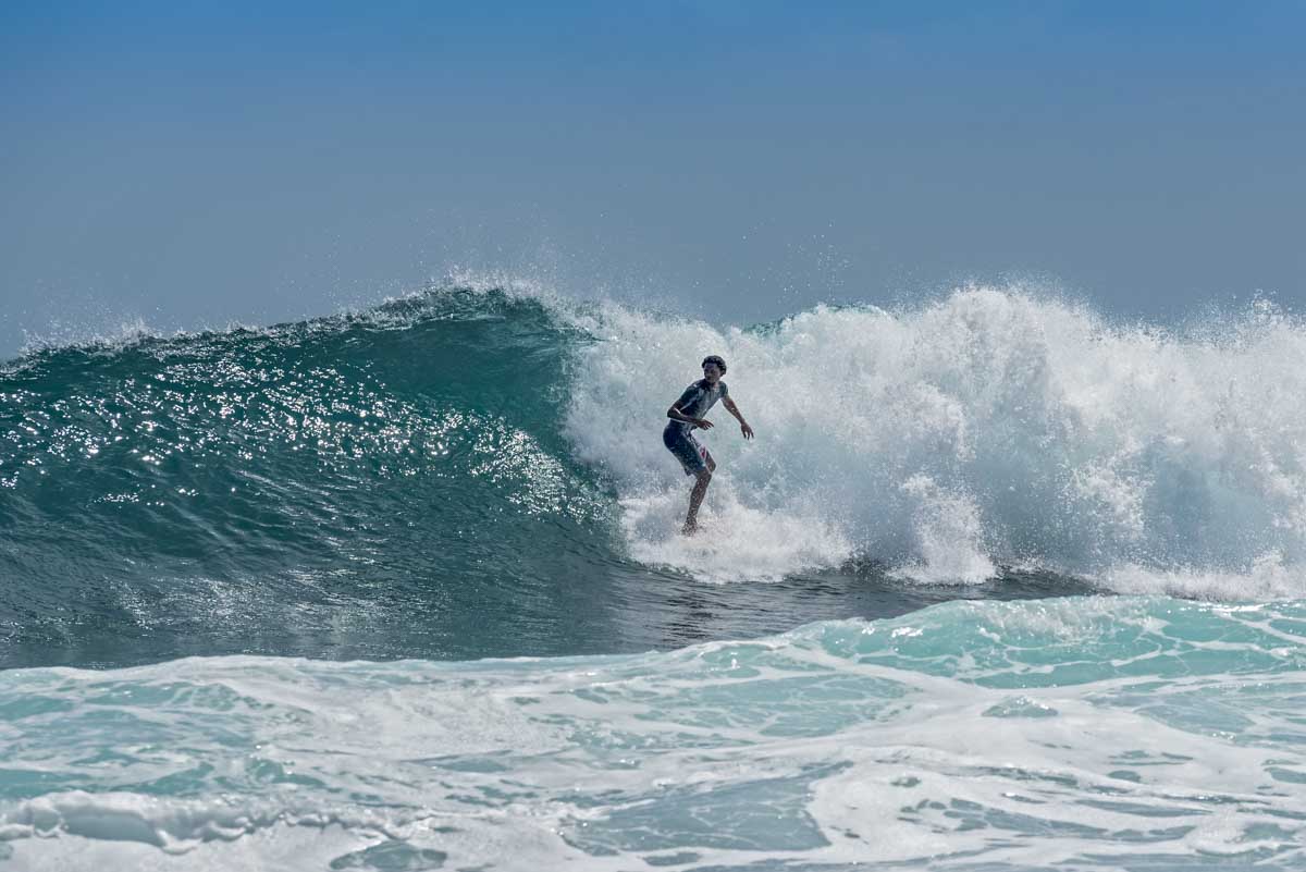 A man surfs a huge wave at Playa Cocles, Puerto Viejo