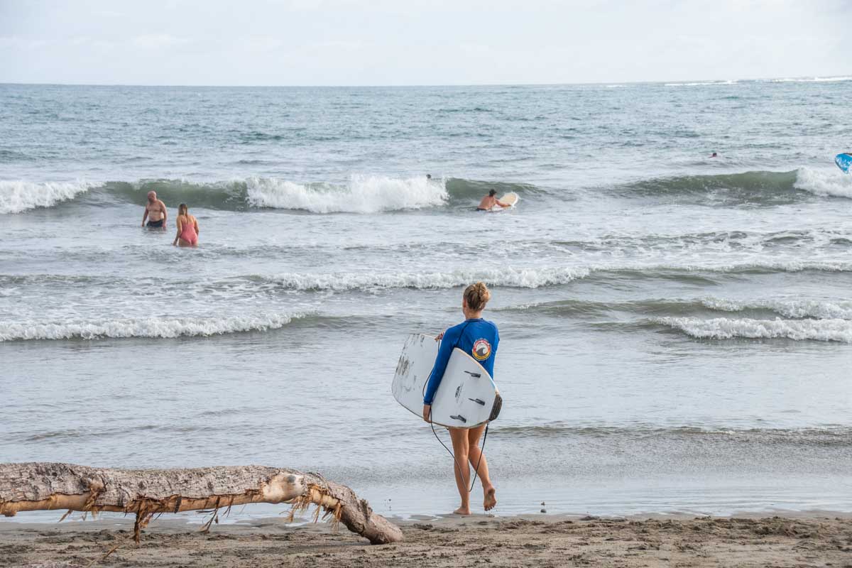 Bailey walks into the water at Samara Beach with a surfboard