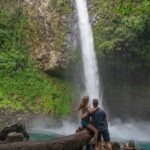 A couple tale a photo below La Fortuna Waterfall