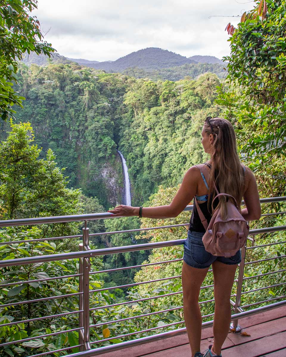A lady stands at the viewpoint overlook La Fortuna Waterfall