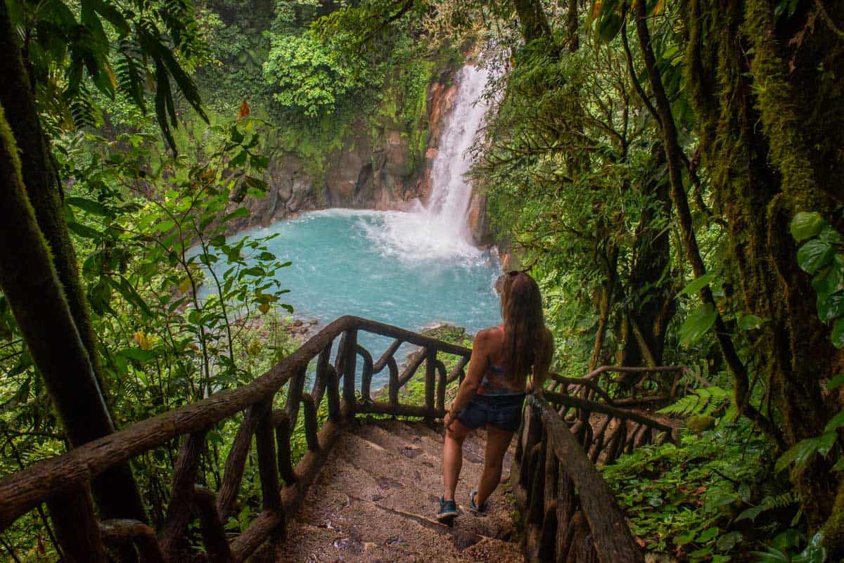 Lady looks down at Rio Celeste Waterfalls from staircase