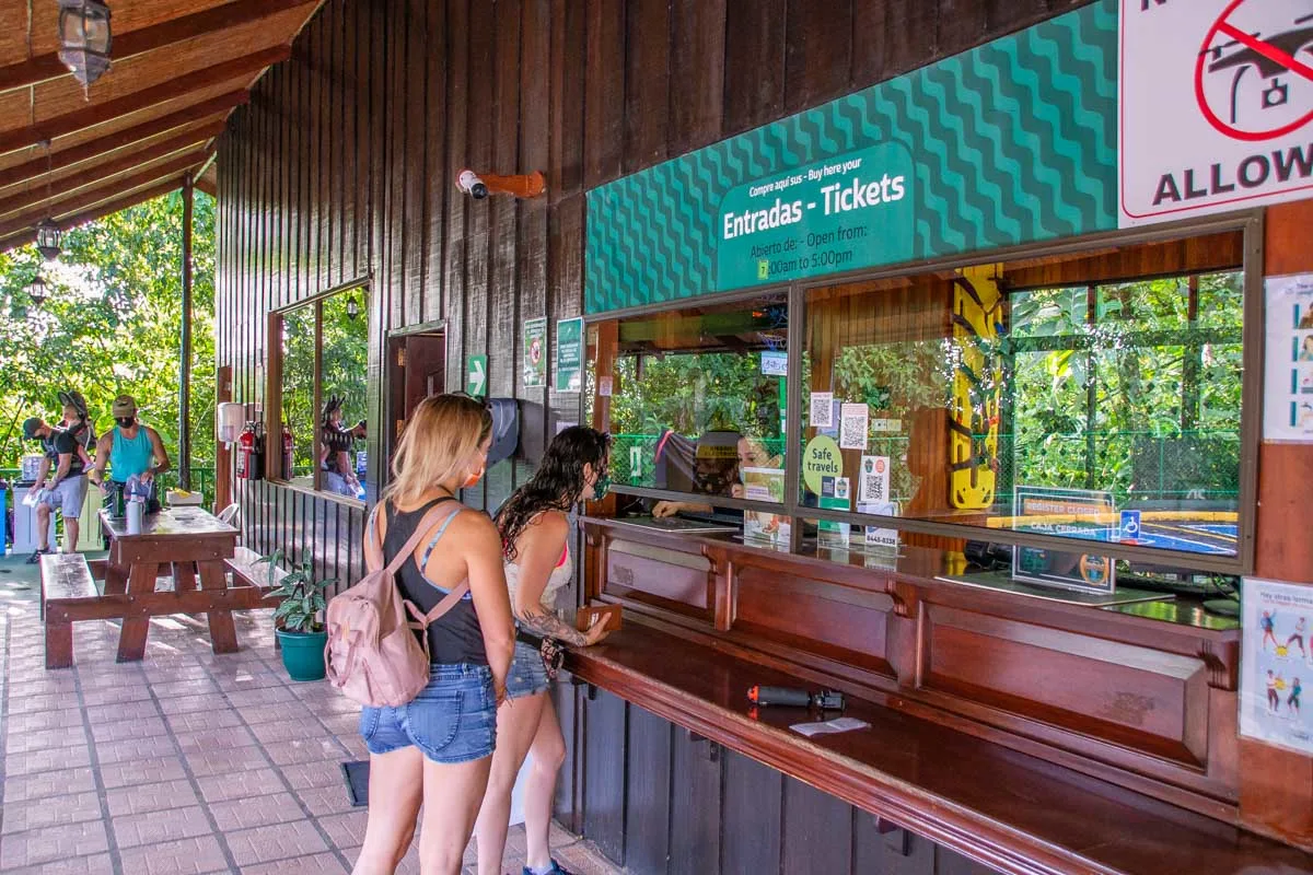 Two people purchase tickets at the entrance to La Fortuna Waterfall