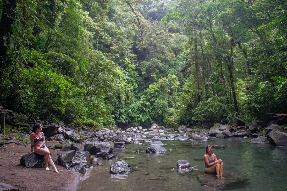 Two people relax at the river near La Fortuna Waterfall, Costa Rica