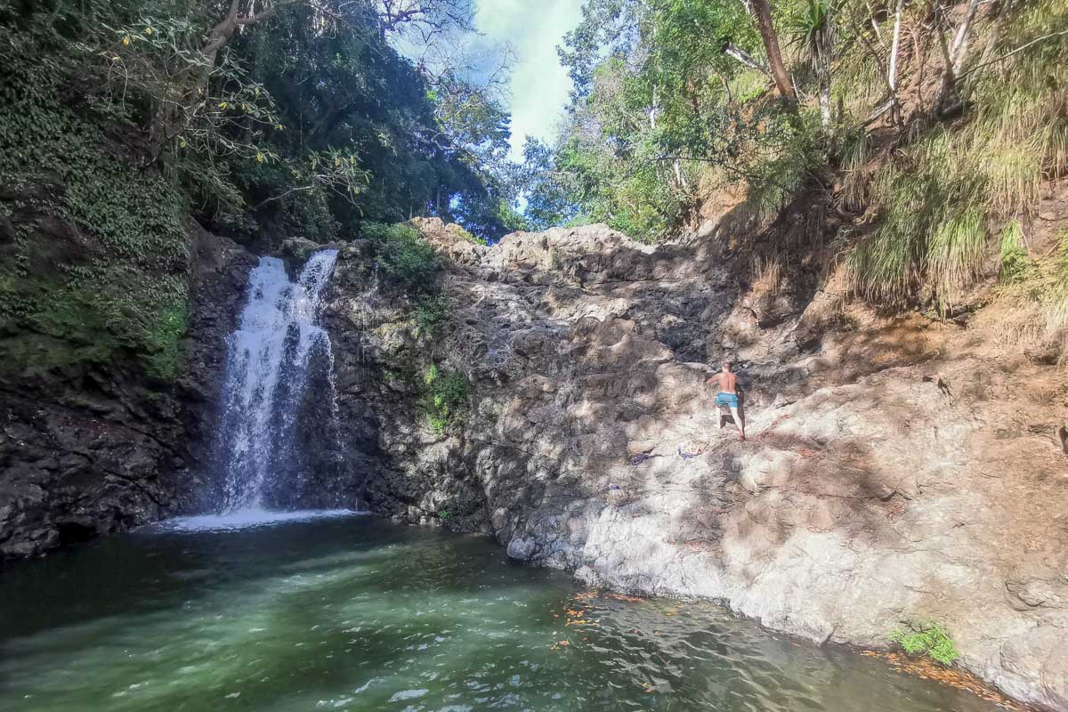 Daniel climbs up a rock face at Montezuma Waterfall in Costa Rica