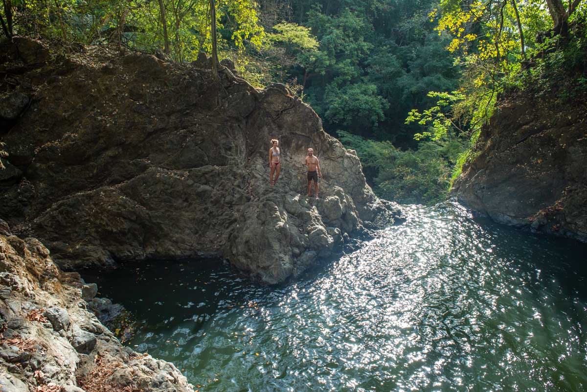 Two people stand at the pool above the lower Montezuma Waterfall in Costa Rica