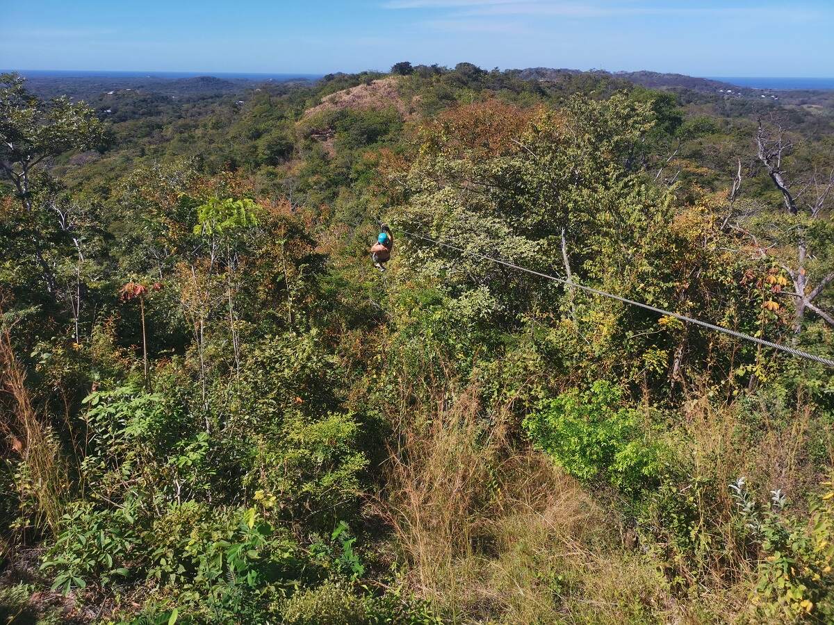 man ziplining over the jungle in Costa Rica with the ocean in the distance!