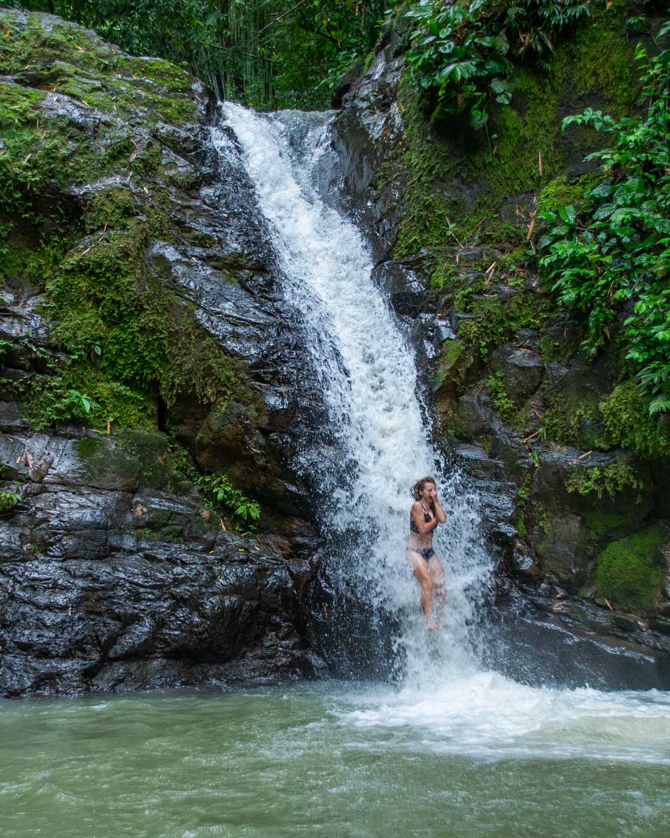 A lady slides down the waterfall at Uvita Waterfall 