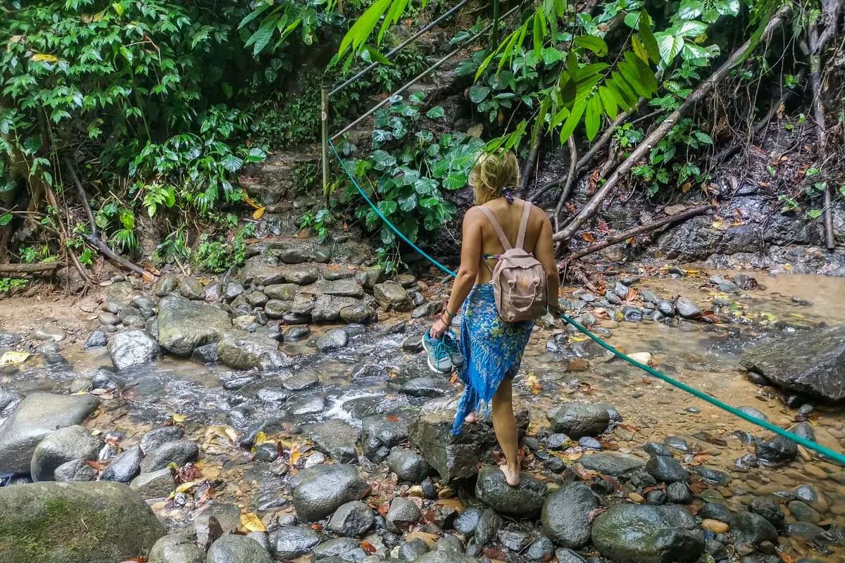 Bailey walks on a trail at Uvita Waterfall over some slippery rocks