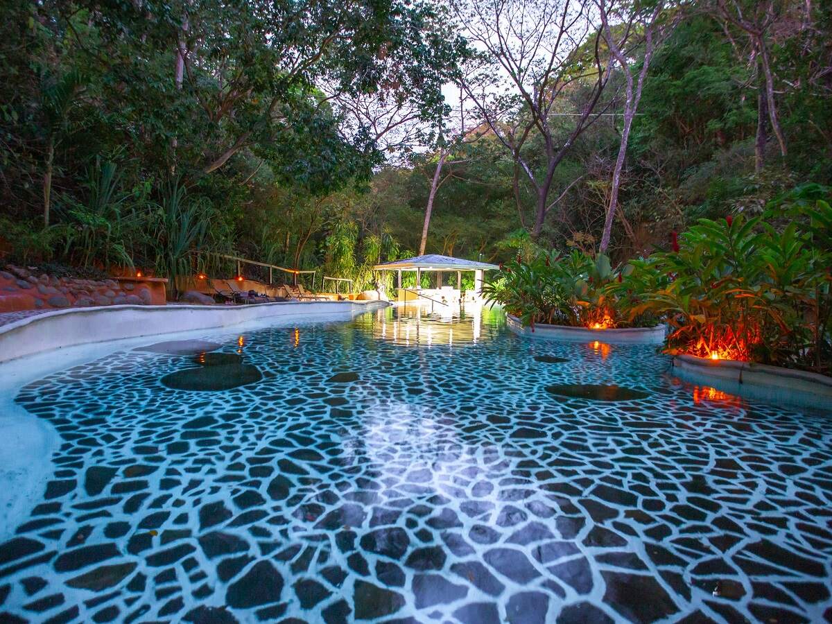 blue hot springs surrounded by jungle in the evening at Vandara Hot Springs