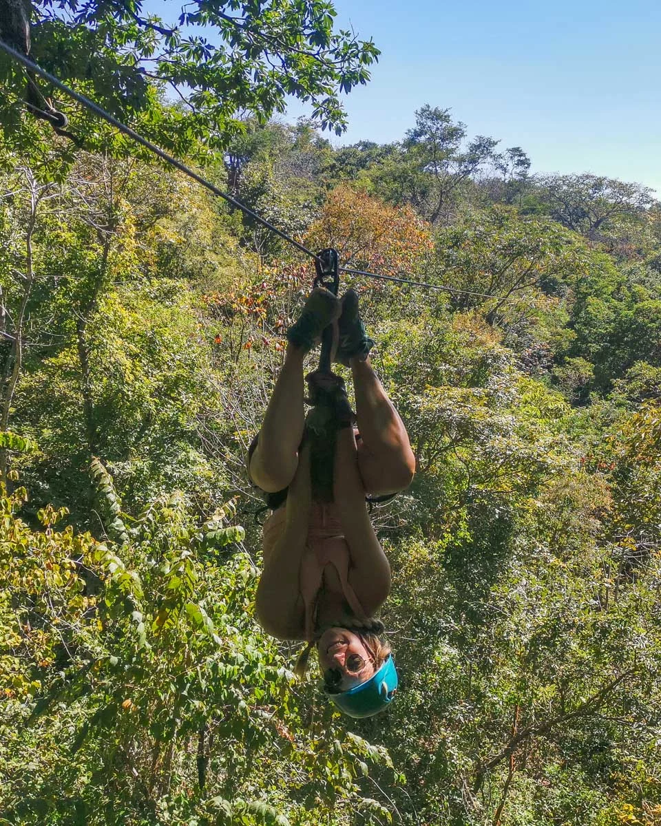 Bailey hangs upside down while ziplining in Costa Rica