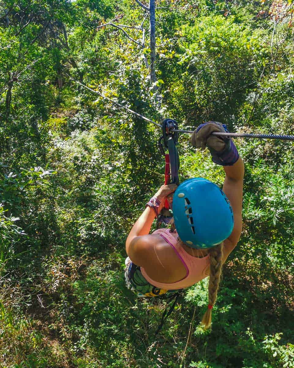 Bailey goes down a zipline surounded by lush green forrrest in Tamarindo, Costa Rica
