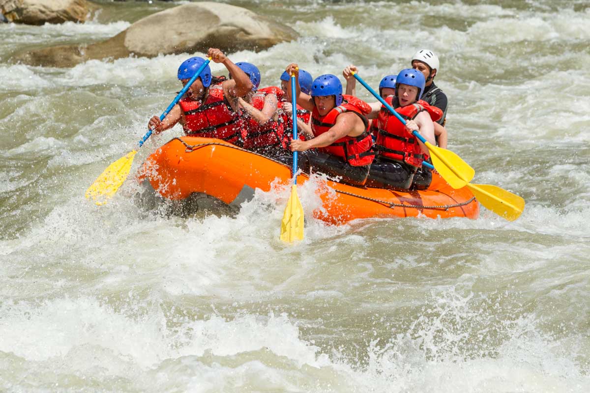 A tour group paddle into a rapid while white water rafting in La Fortuna, Costa Rica