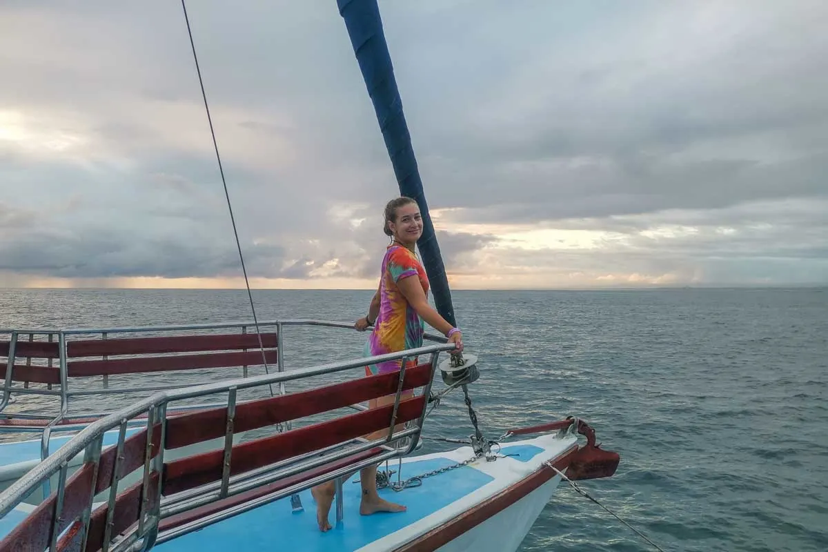 Bailey stands at the front of the boat on a sunset cruise in Tamarindo