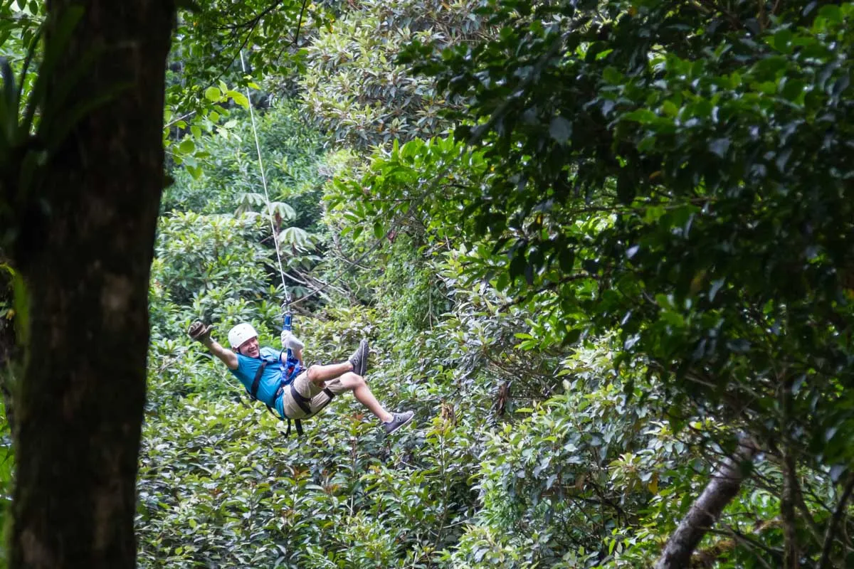 A man gives a thumbs up while ziplining in la fortuna