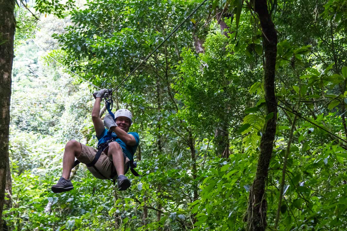 A man prepairs to stop while ziplining in La Fortuna, Costa Rica